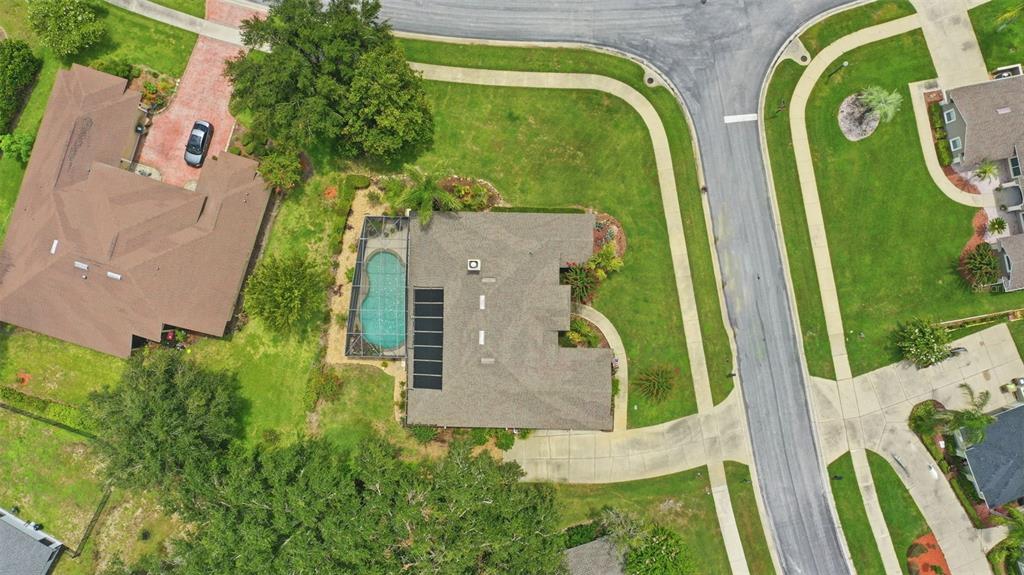 An aerial view shows a house with a screened pool and solar panels on the roof — 11310 SUSANS POINT DRIVE, CLERMONT, FL