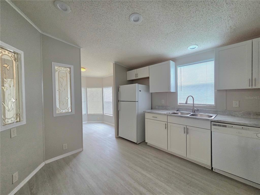A kitchen with white cabinets, white appliances, and light wood-look flooring — 2253 & 2249 GOLFVIEW STREET, LAKELAND, FL