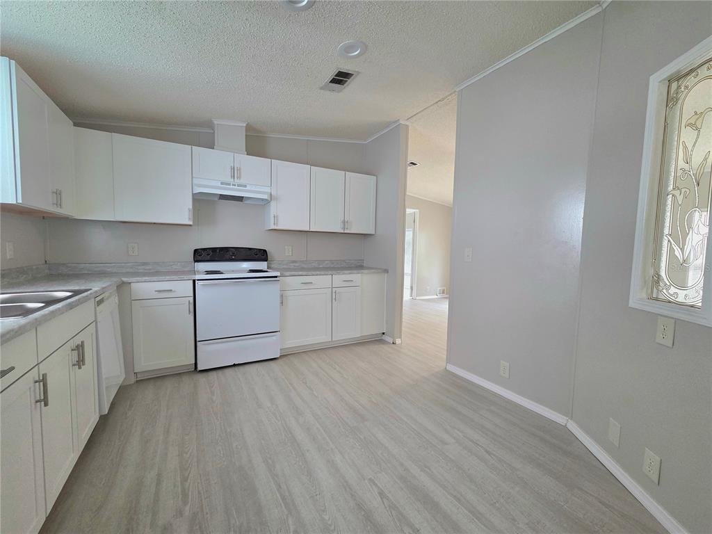 A kitchen features white cabinets, a white stove, and light wood-look flooring — 2253 & 2249 GOLFVIEW STREET, LAKELAND, FL