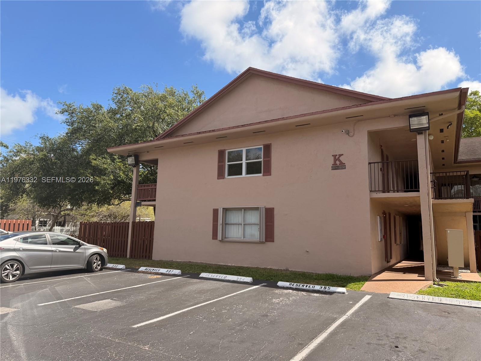 A two-story tan apartment building with a parking lot in the foreground — 11279 SW 88th St # 210K, Miami FL 33176, MIAMI, FL