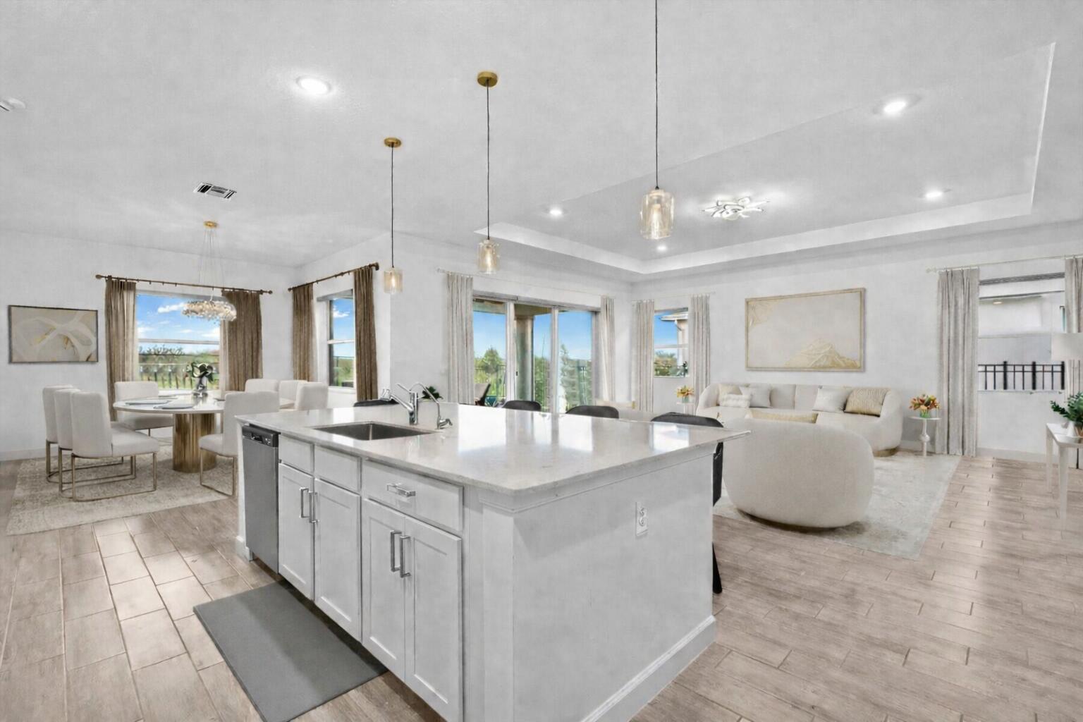 A bright open-concept kitchen with a white island and dining area overlooking a living room — 1130 Tangled Orchard Trace, FL 33470, FL