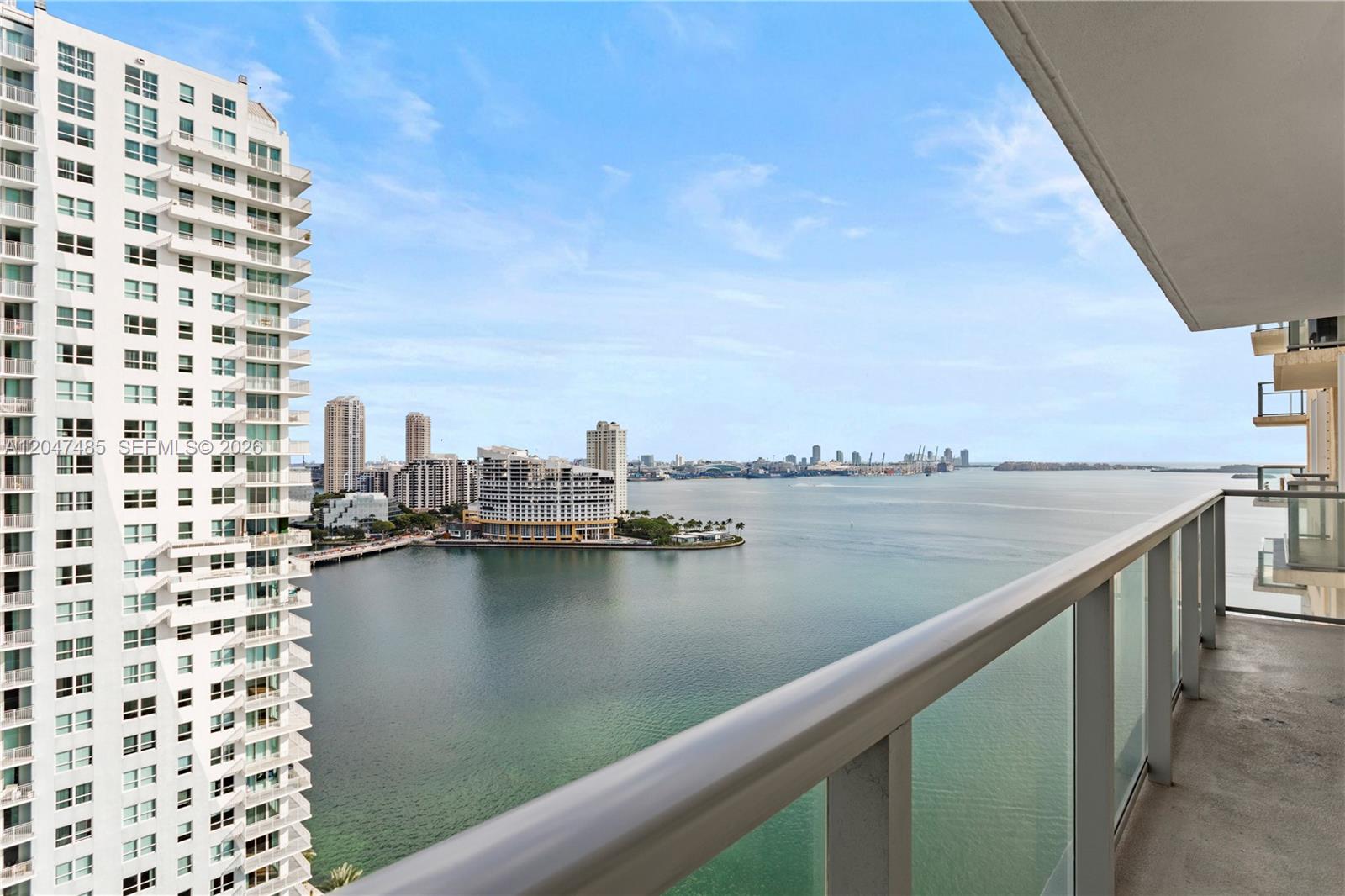 A balcony view overlooking a bay with a tall residential building and city skyline — 1155 Brickell Bay Dr # 2206, Miami FL 33131, MIAMI, FL