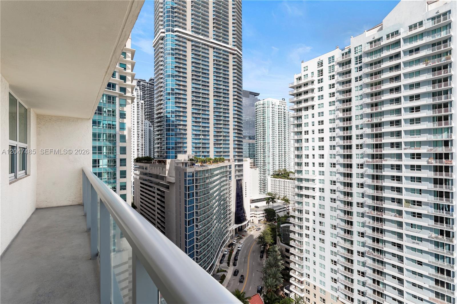 A balcony overlooks a dense urban landscape featuring several tall residential skyscrapers and a street — 1155 Brickell Bay Dr # 2206, Miami FL 33131, MIAMI, FL