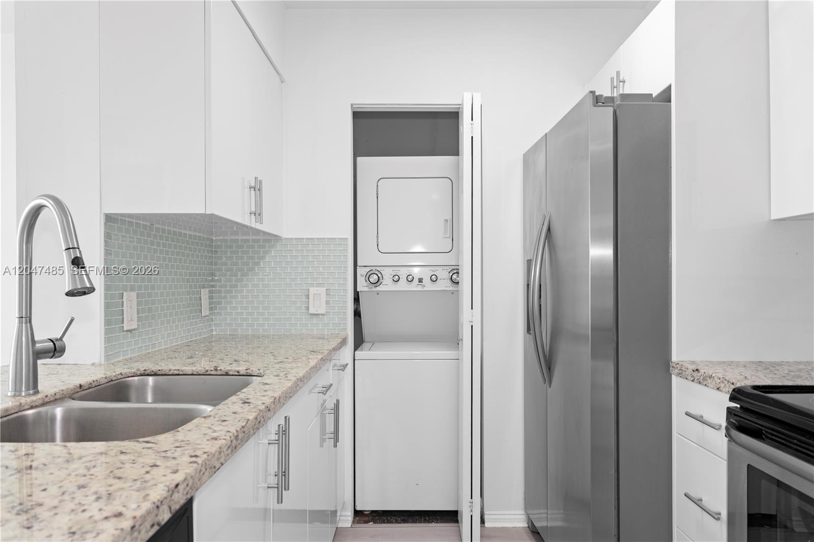 A kitchen features white cabinets, granite countertops, a stainless steel refrigerator, and a stacked laundry unit — 1155 Brickell Bay Dr # 2206, Miami FL 33131, MIAMI, FL