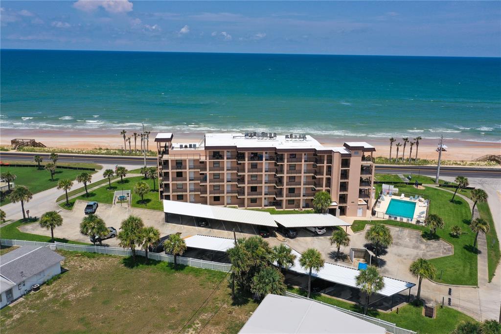 An aerial view shows a multi-story apartment building with a pool and covered parking — 2390 OCEAN SHORE BOULEVARD UNIT 1040, ORMOND BEACH, FL
