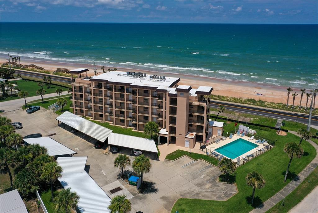 An aerial view shows a multi-story apartment building with a pool and covered parking — 2390 OCEAN SHORE BOULEVARD UNIT 1040, ORMOND BEACH, FL