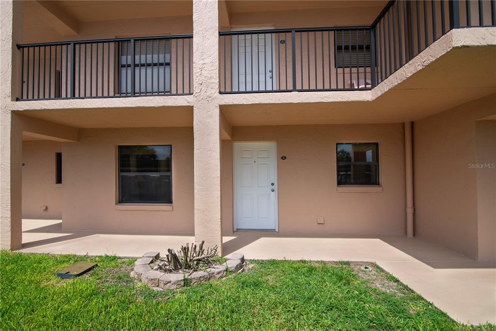 A two-story tan stucco building exterior features a ground-level patio and an upper-level balcony — 2390 OCEAN SHORE BOULEVARD UNIT 1040, ORMOND BEACH, FL