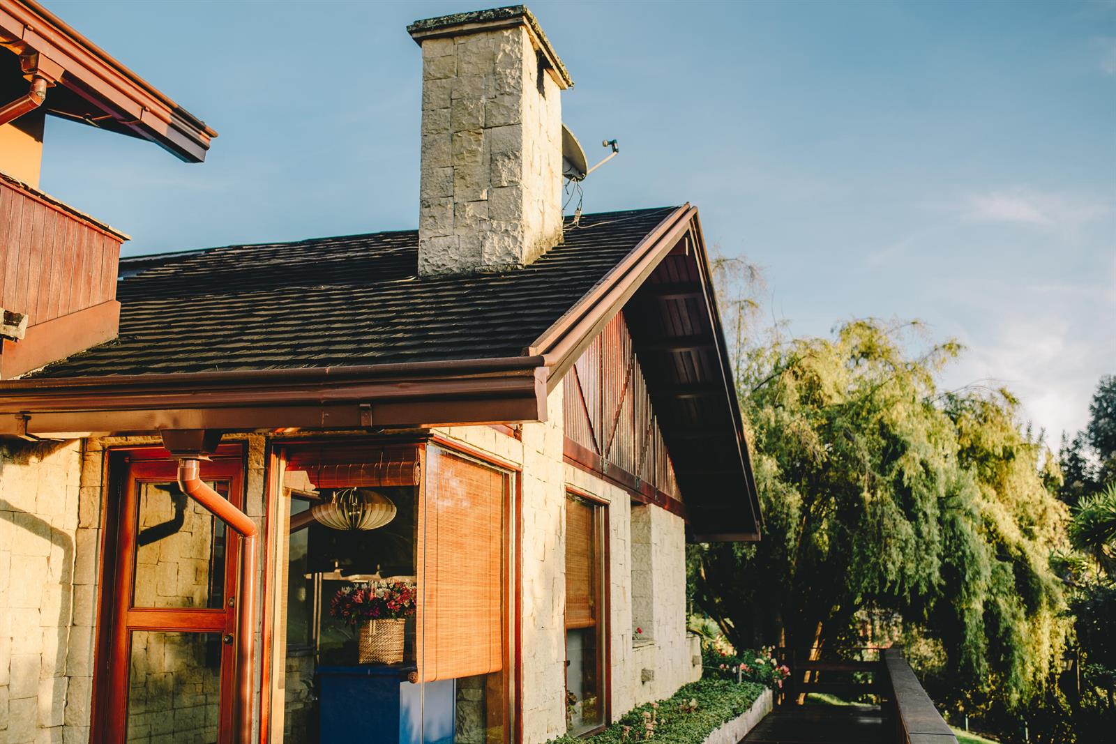 A stone house exterior features a chimney, dark roof shingles, and a wooden deck — 43 Altos De Yerbabuena # 43, FL