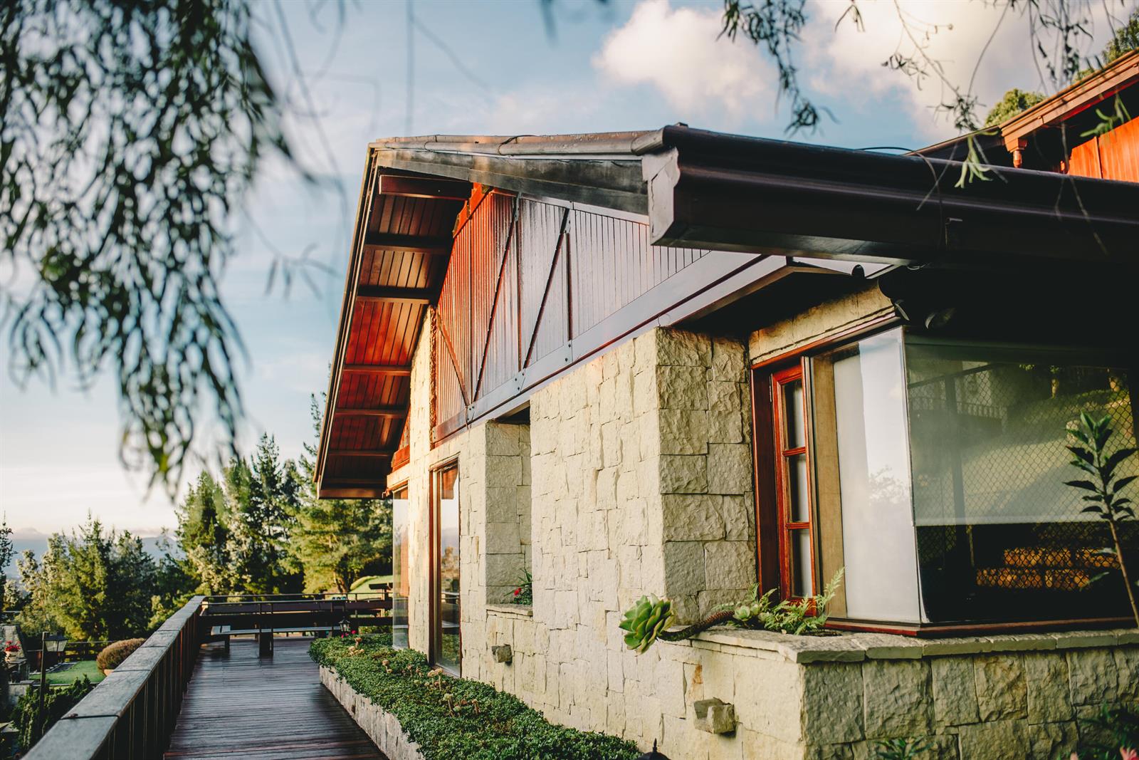 A stone-walled house with a wooden deck and overhanging roof sits on a hillside — 43 Altos De Yerbabuena # 43, FL