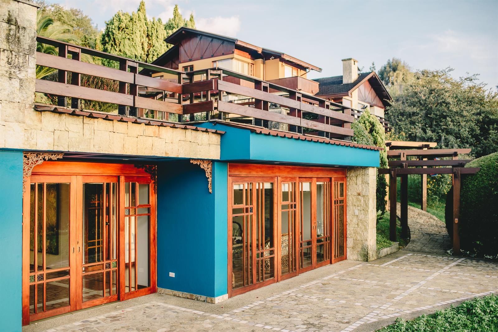 A two-story house with blue walls, stone accents, wooden balconies, and large glass-paneled doors — 43 Altos De Yerbabuena # 43, FL