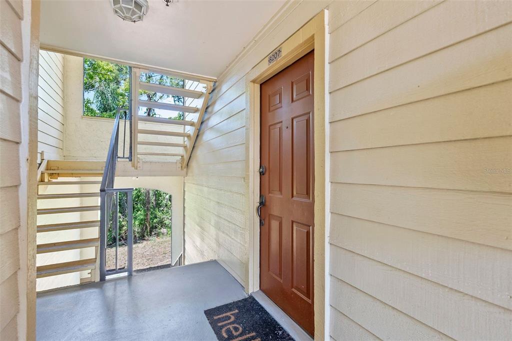 An exterior view of a building entrance with a brown door and a metal staircase — 11901 4TH STREET N UNIT 8207, ST PETERSBURG, FL