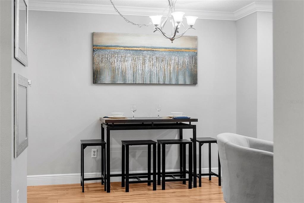 A dining area features a dark metal table with four stools under a chandelier — 11901 4TH STREET N UNIT 8207, ST PETERSBURG, FL