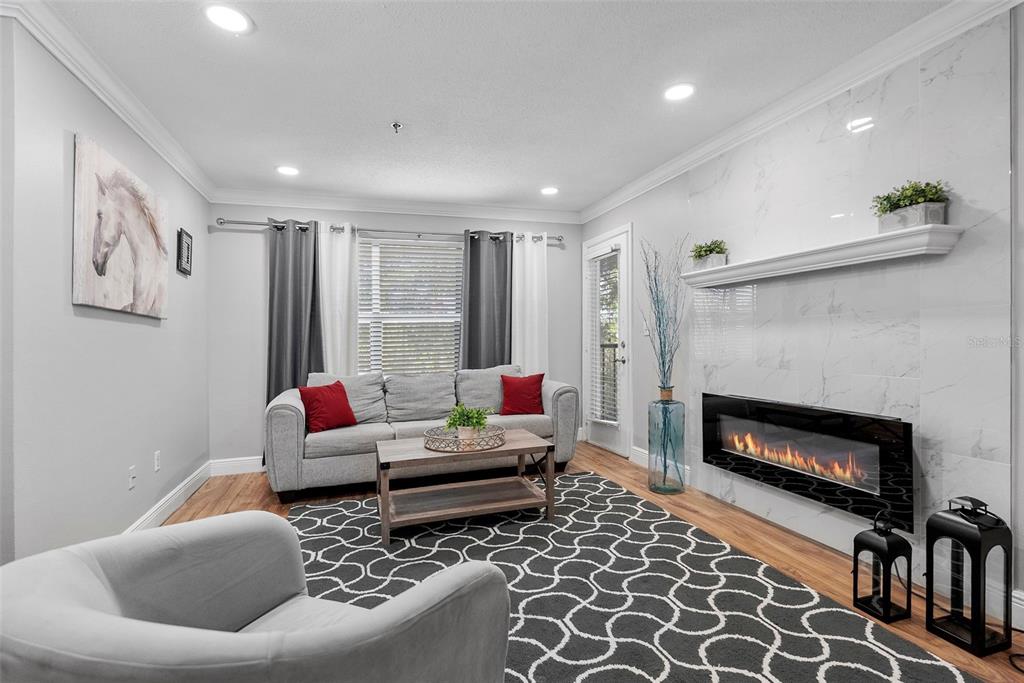 A living room features a gray sofa, a fireplace with a marble surround, and patterned flooring — 11901 4TH STREET N UNIT 8207, ST PETERSBURG, FL
