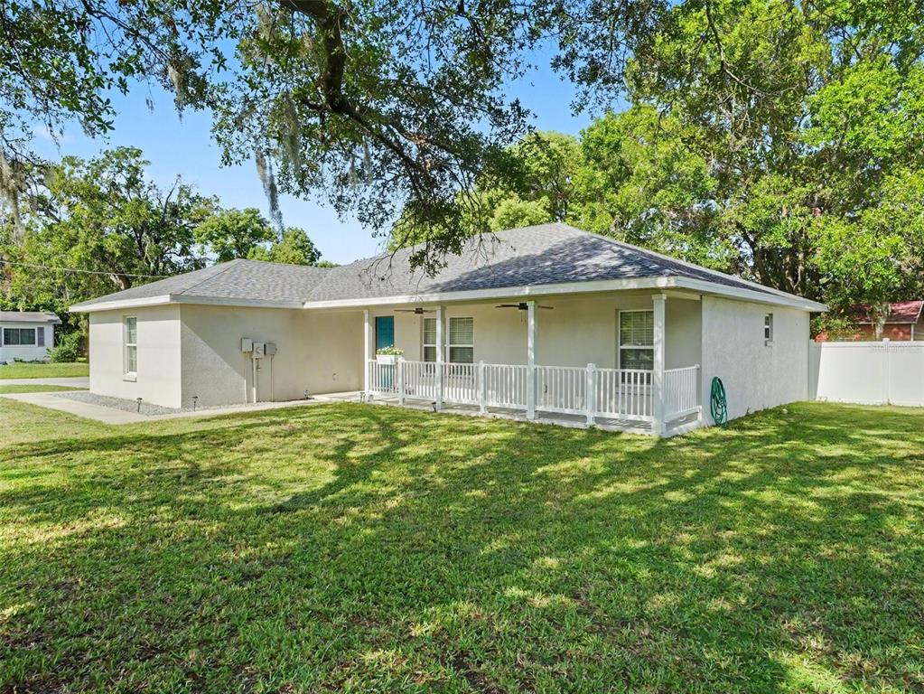 A single-story house with a white stucco exterior, a covered front porch, and a grassy yard — 410 NE 12TH AVENUE, MULBERRY, FL