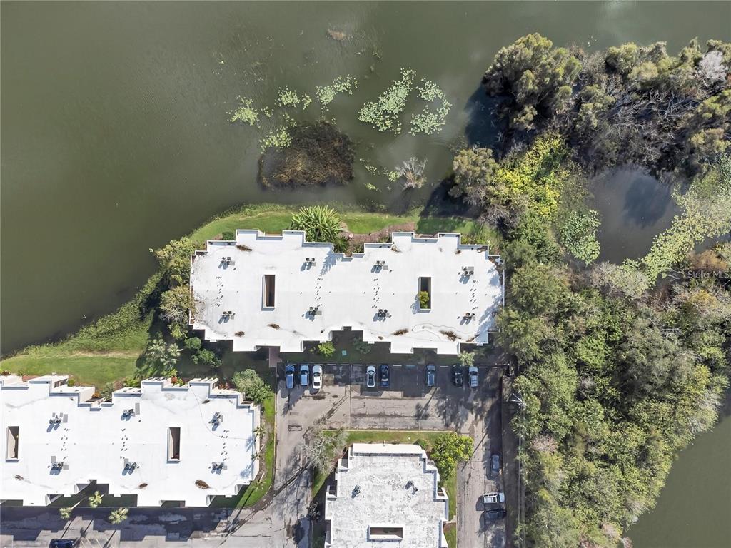 An aerial view shows several multi-story buildings with flat roofs situated near a lake — 542 ORANGE DRIVE UNIT 26, ALTAMONTE SPRINGS, FL