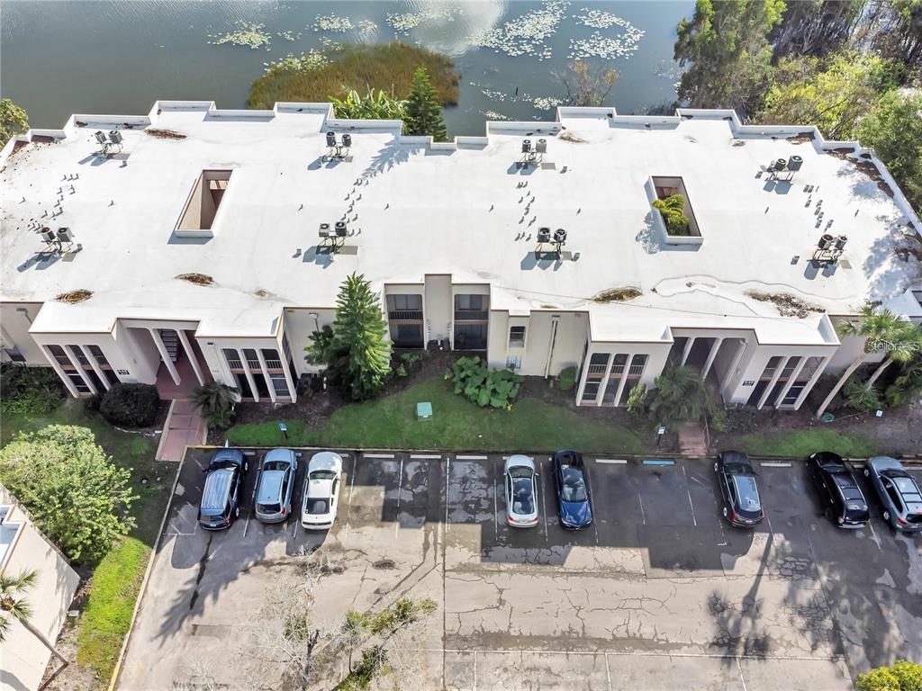 An aerial view shows a multi-unit residential building with a flat roof, parking lot, and lake — 542 ORANGE DRIVE UNIT 26, ALTAMONTE SPRINGS, FL