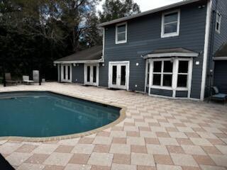 A two-story house with dark siding features a paved patio and an in-ground swimming pool — 4332 145th Avenue N, FL 33470, FL