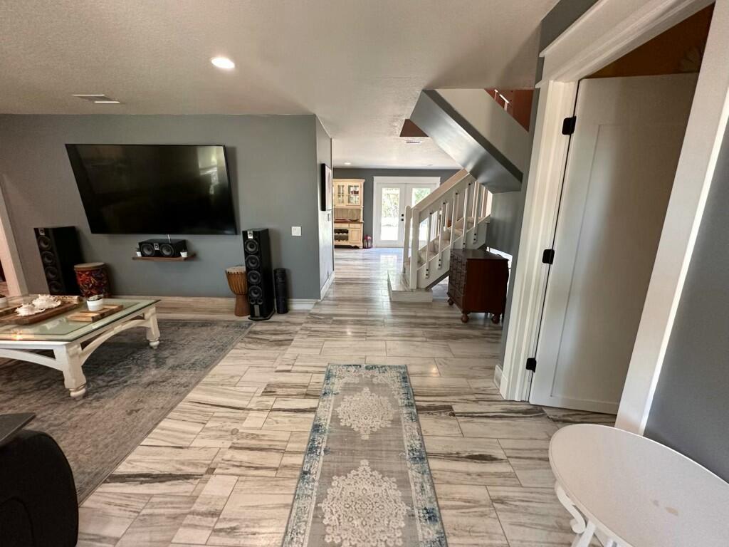 A living room with gray walls, wood-look tile floors, and a staircase leads to an entryway — 4332 145th Avenue N, FL 33470, FL