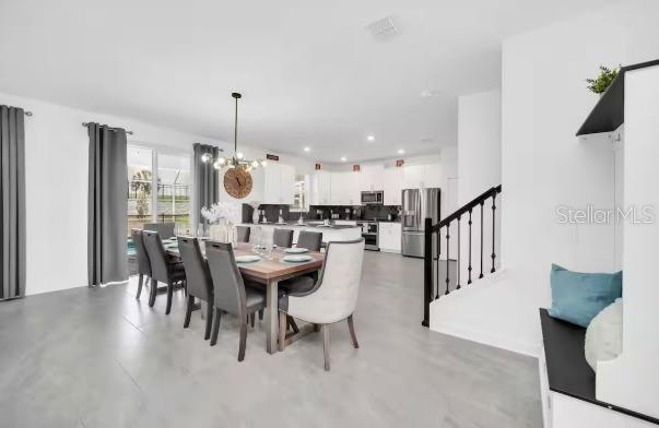 An open-concept dining area with a wooden table and chairs next to a modern kitchen — 9092 SOMMERSET HILLS DRIVE, DAVENPORT, FL