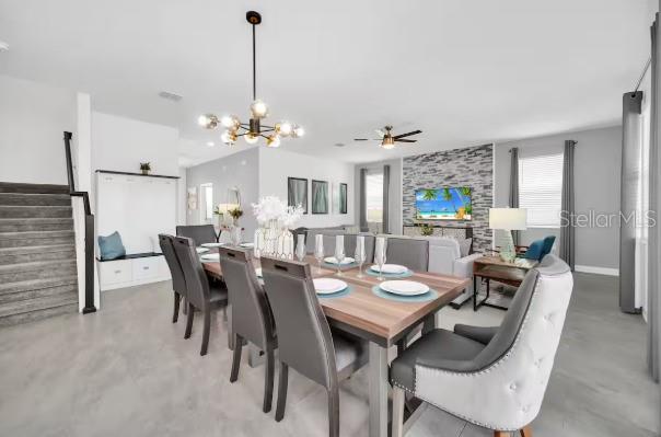 A dining area features a wooden table with eight chairs, a chandelier, and a stone fireplace — 9092 SOMMERSET HILLS DRIVE, DAVENPORT, FL