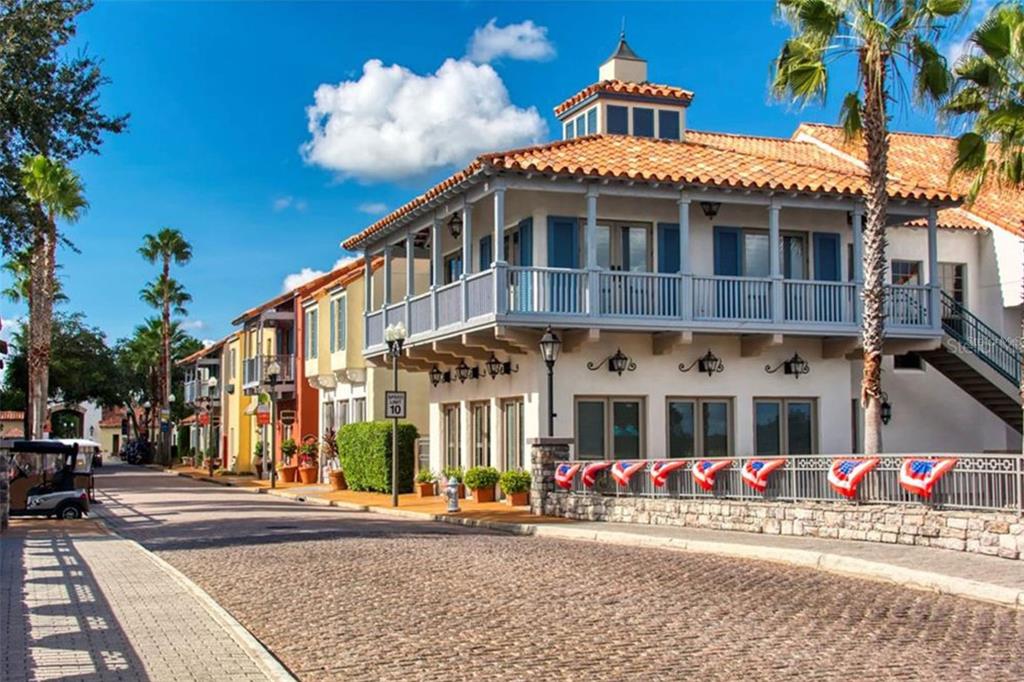 A multi-story building with a terracotta roof and a balcony stands along a cobblestone street — 1192 VIA GALUPPI STREET, KISSIMMEE, FL