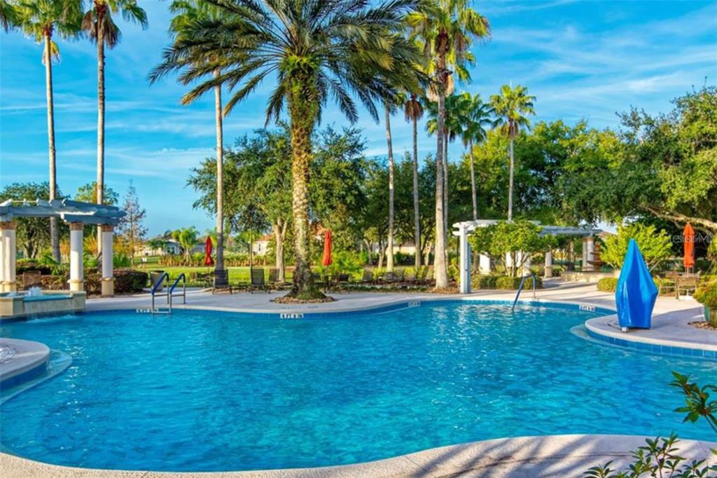 A swimming pool with a surrounding patio, palm trees, and pergolas under a blue sky — 1192 VIA GALUPPI STREET, KISSIMMEE, FL