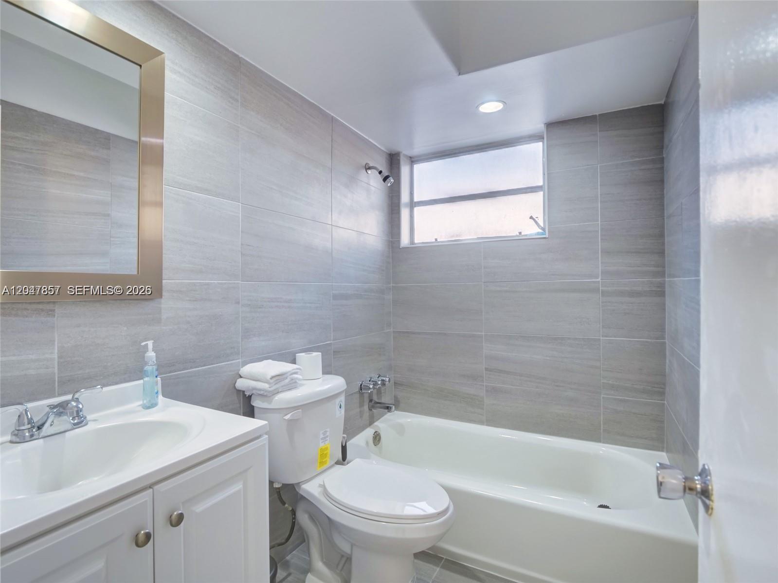 A bathroom features a white vanity, a toilet, and a tiled bathtub shower combination — 1141 NW 75th St, Miami FL 33150, MIAMI, FL