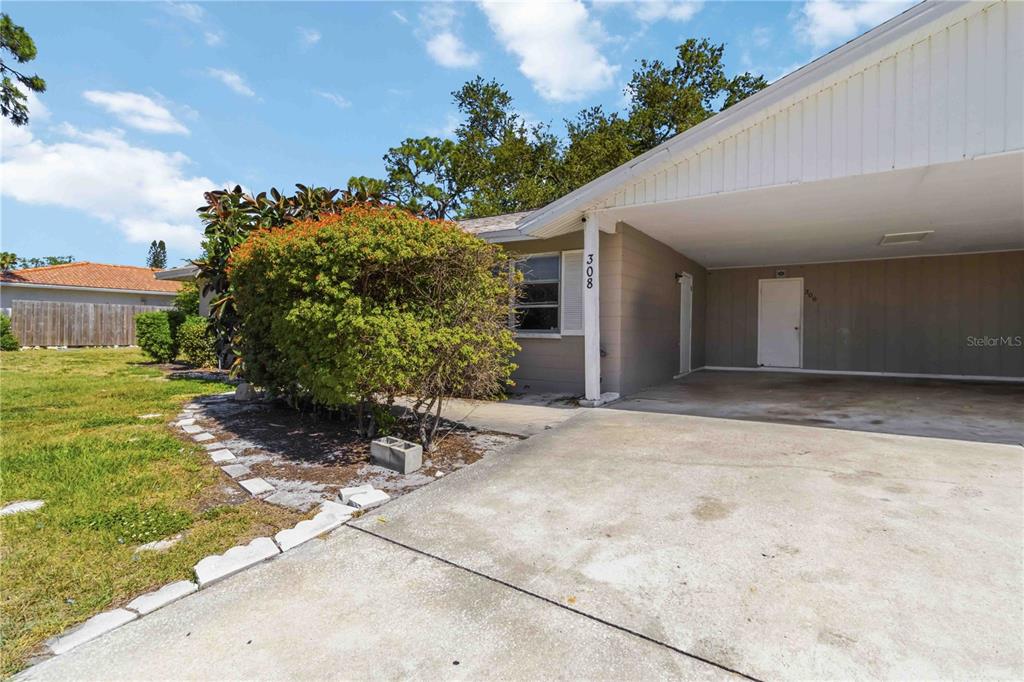 A single-story house with a concrete driveway, a carport, and a large bush in front — 308 LANTANA AVENUE, SARASOTA, FL