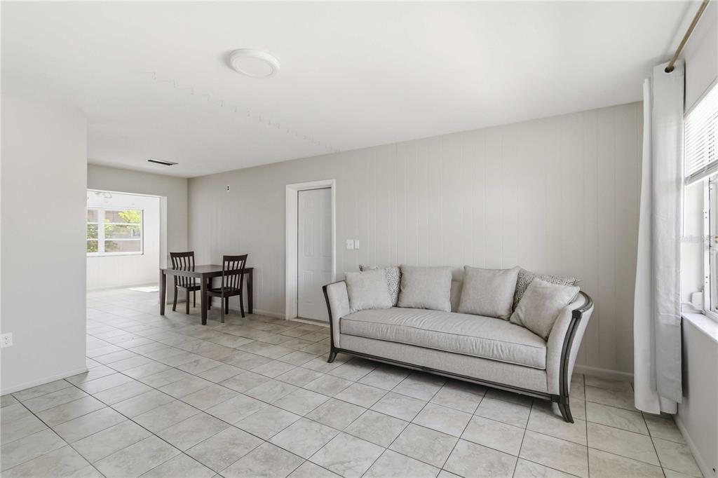 A living room with light tile flooring, a gray sofa, and a dining area beyond — 308 LANTANA AVENUE, SARASOTA, FL
