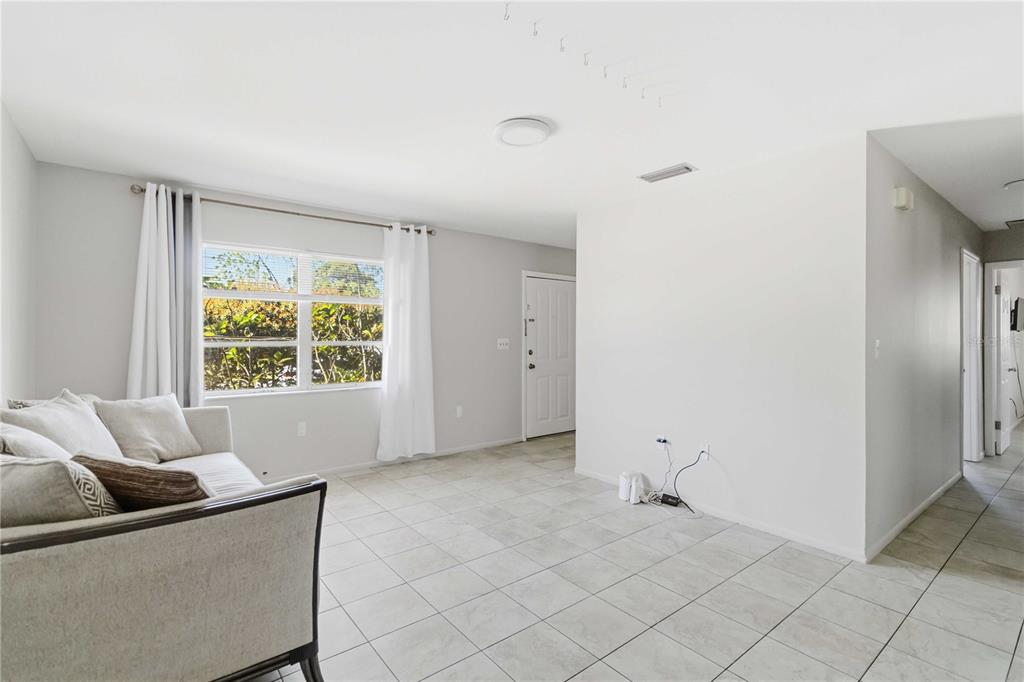 A living room with light tile flooring, a white sofa, and a large window — 308 LANTANA AVENUE, SARASOTA, FL