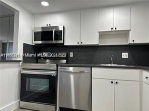A kitchen features white cabinets, stainless steel appliances, and a dark countertop — 13499 Biscayne Blvd # 801, North Miami FL 33181, NORTH MIAMI, FL