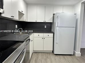 A kitchen featuring white cabinets, a dark countertop, a stainless steel sink, and a white refrigerator — 13499 Biscayne Blvd # 801, North Miami FL 33181, NORTH MIAMI, FL