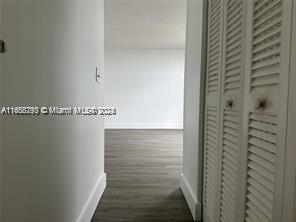 A hallway with wood-look flooring leads to an open room with white walls and doors — 13499 Biscayne Blvd # 801, North Miami FL 33181, NORTH MIAMI, FL