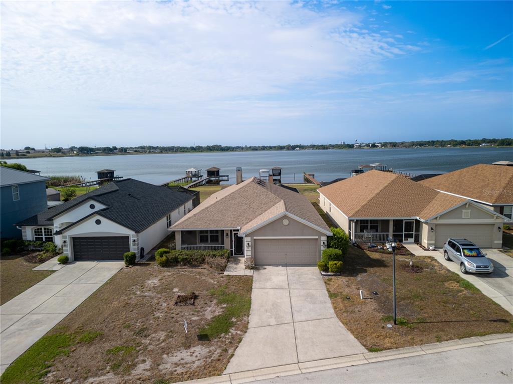 An aerial view shows three suburban houses with driveways facing a large lake — 3971 ISLAND LAKES DRIVE, WINTER HAVEN, FL