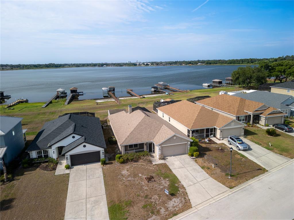 An aerial view shows three suburban houses with driveways facing a large lake — 3971 ISLAND LAKES DRIVE, WINTER HAVEN, FL