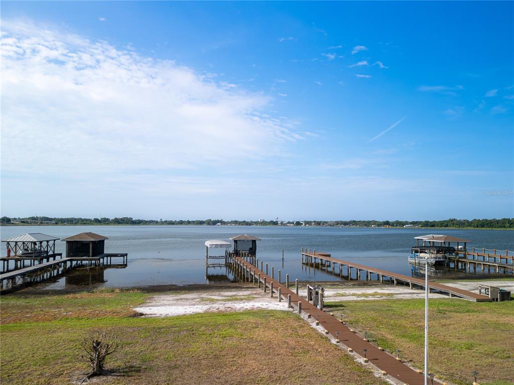 A view of a lake with three wooden boat docks extending from a grassy shore — 3971 ISLAND LAKES DRIVE, WINTER HAVEN, FL