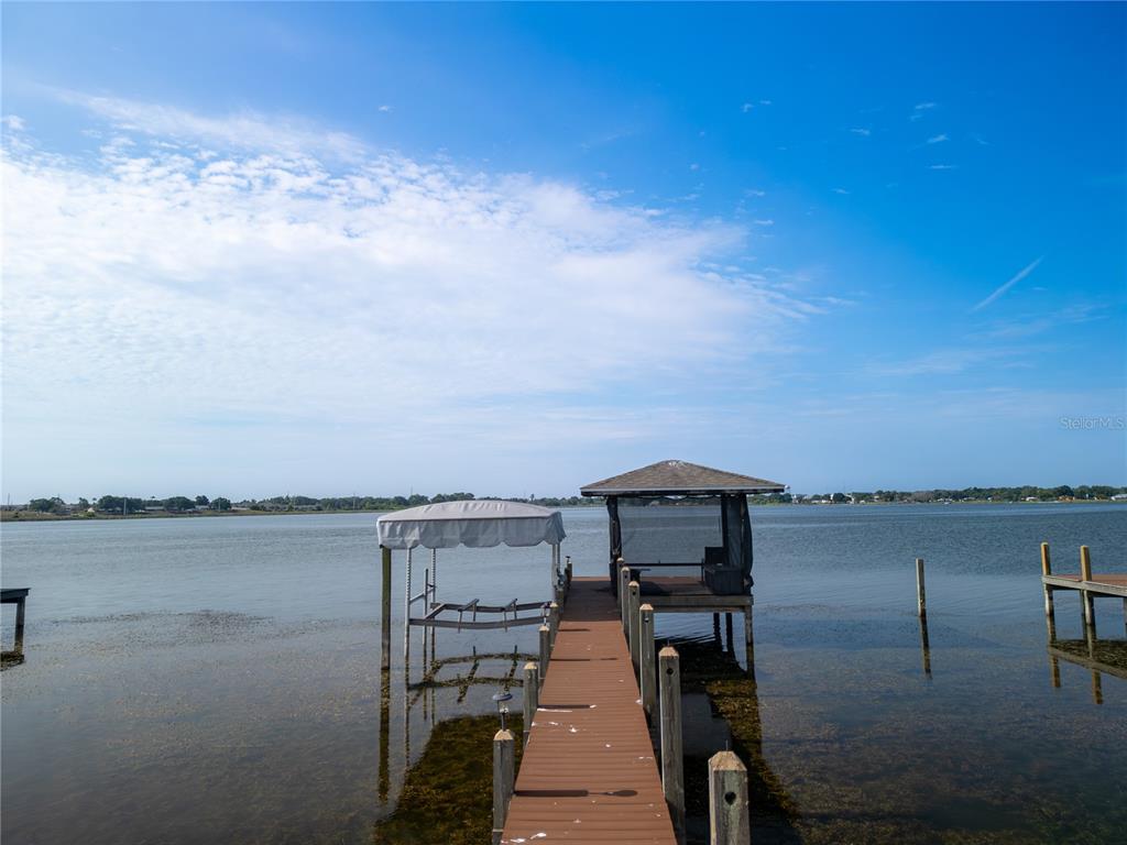 A wooden dock extends into a lake with a boat lift and a covered gazebo — 3971 ISLAND LAKES DRIVE, WINTER HAVEN, FL