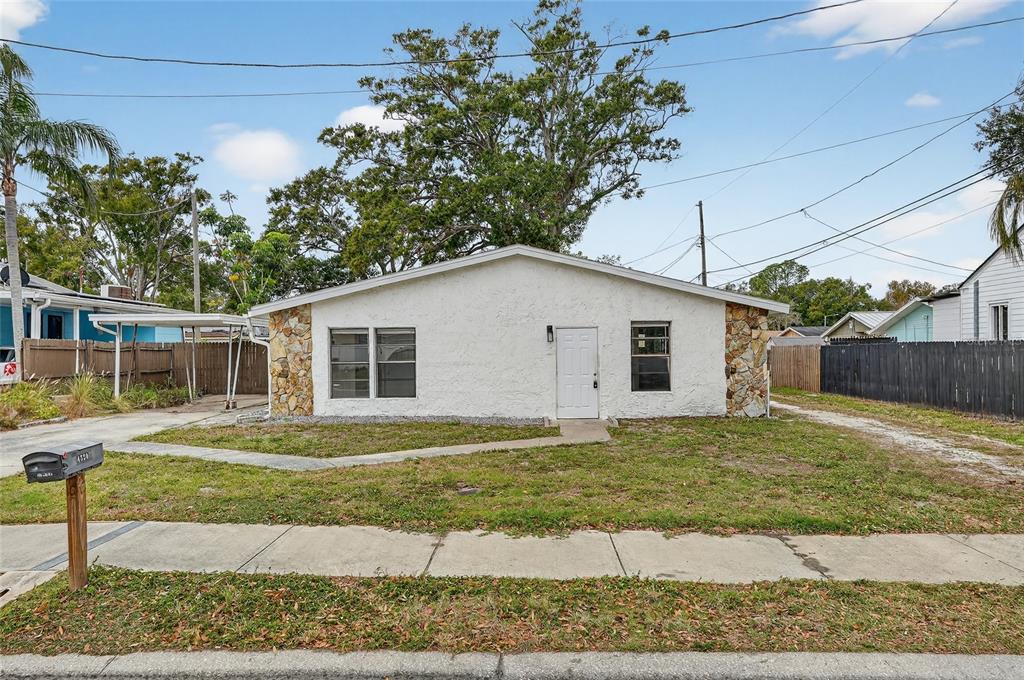 A single-story house with white stucco walls, stone accents, and a front-facing door — 4320 44TH STREET N, ST PETERSBURG, FL