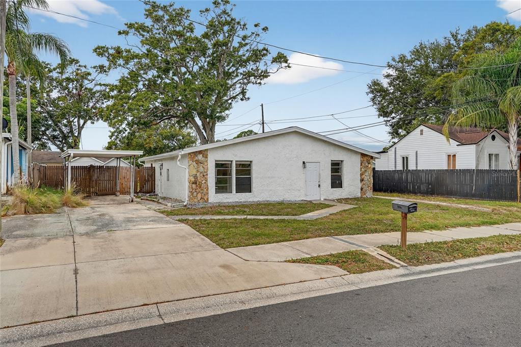 A single-story white house with stone accents, a carport, and a concrete driveway — 4320 44TH STREET N, ST PETERSBURG, FL