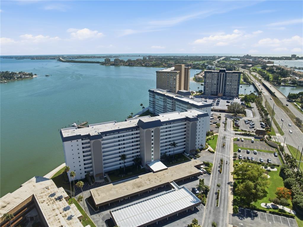 An aerial view shows a multi-story apartment complex situated along a waterfront with parking — 5108 BRITTANY DRIVE S UNIT 506, ST PETERSBURG, FL