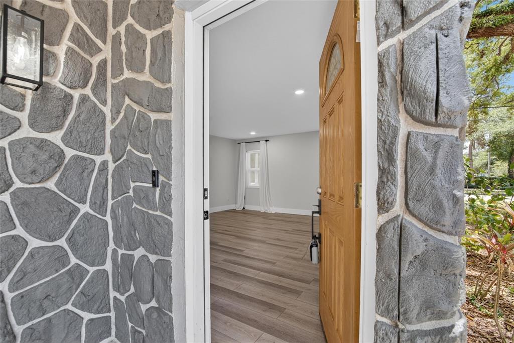 A view through an open wooden door reveals a room with light wood-look flooring — 5326 S RUSSELL STREET, TAMPA, FL