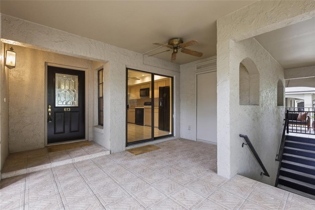 A covered entryway features a tiled floor, a dark front door, and a sliding glass door — 1055 KENSINGTON PARK DRIVE UNIT 613, ALTAMONTE SPRINGS, FL