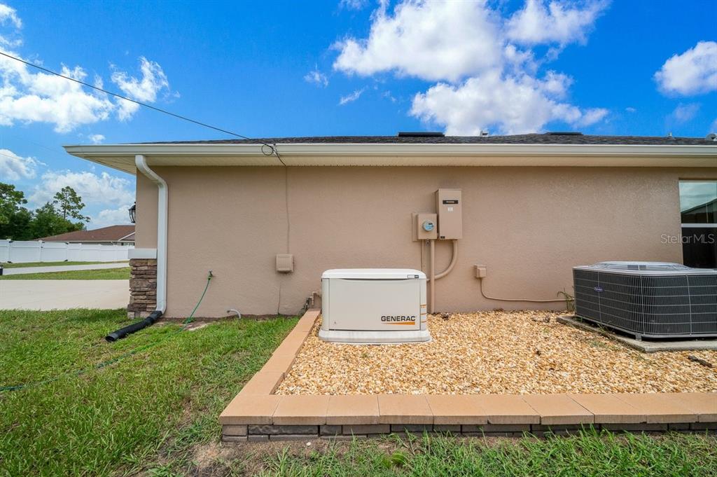 A Generac generator and an air conditioning unit sit on a gravel pad outside — 8828 SE 160TH PLACE, SUMMERFIELD, FL