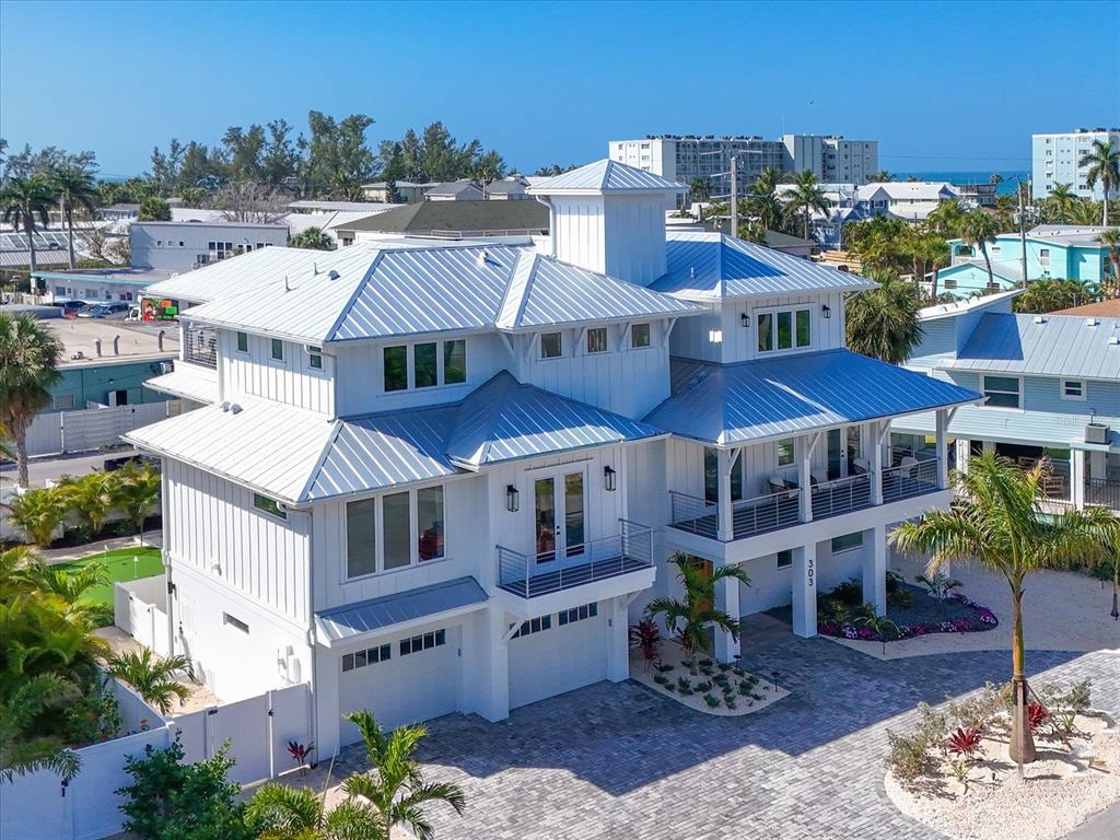 An elevated white coastal home with a metal roof and a paved driveway — 303 55TH STREET, HOLMES BEACH, FL