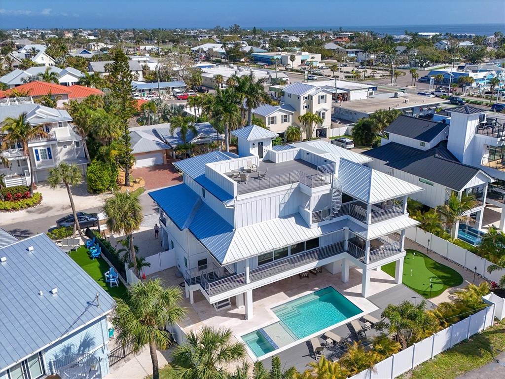 An aerial view of a multi-story coastal home featuring a swimming pool and rooftop deck — 303 55TH STREET, HOLMES BEACH, FL