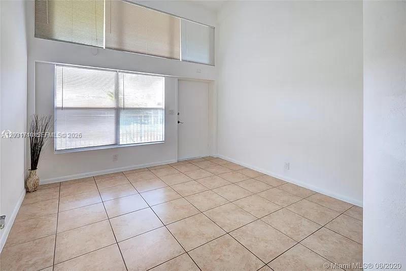 An empty room features beige tile flooring, white walls, and a large window with blinds — 4121 NW 26th St # T14, Lauderhill FL 33313, LAUDERHILL, FL