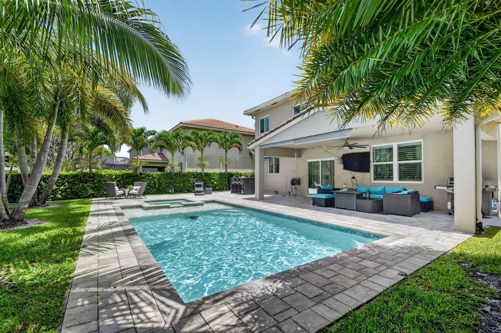 A backyard features a rectangular swimming pool, a hot tub, and a covered patio area — 8890 Cobblestone Point Circle, Boynton Beach FL 33472, BOYNTON BEACH, FL