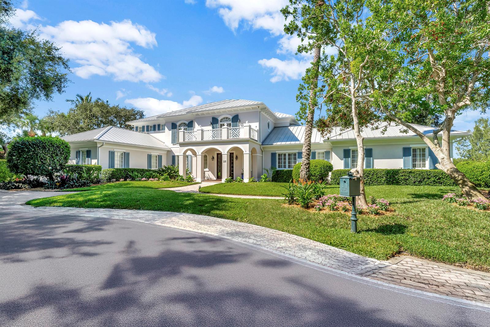 A two-story house with a metal roof, white exterior, and a circular driveway — VERO BEACH, FL