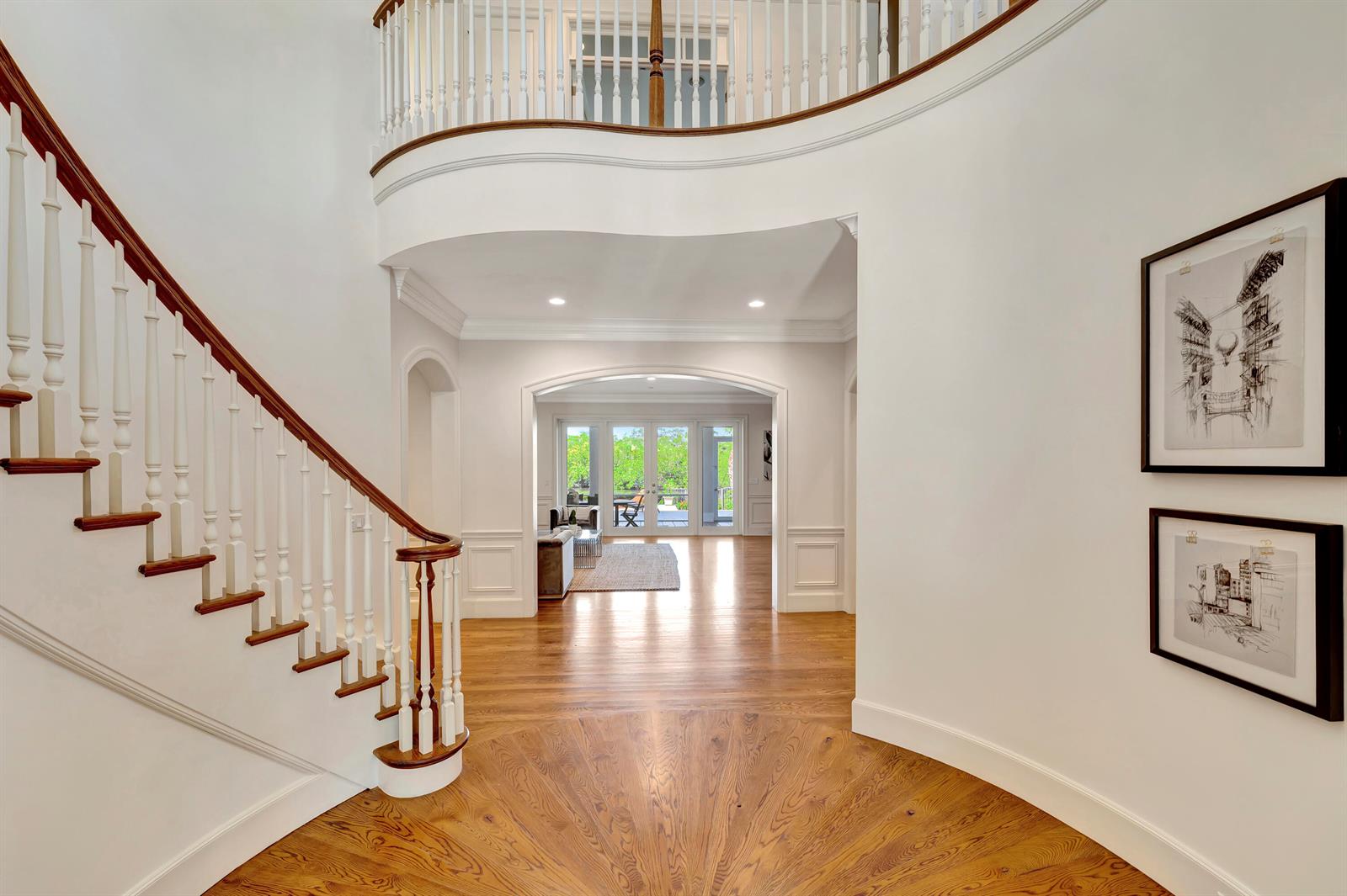 A grand foyer features a curved staircase, hardwood floors, and an arched entryway to a room — VERO BEACH, FL