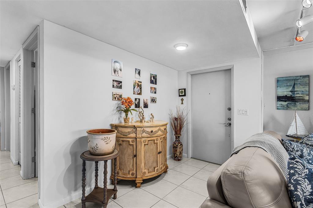 An entryway features a light-colored wooden cabinet, a small side table, and tiled flooring — 3831 SE 11TH PLACE UNIT 101, CAPE CORAL, FL